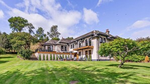 A large, two-story house with a covered patio, a well-maintained lawn, and a variety of trees. - 6 Bed in Perth (oc-96289) (Stanley)