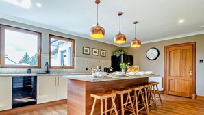A modern kitchen with a central island, bar stools, pendant lights, a clock, and a window. - 6 Bed in Perth (oc-96289) (Stanley)