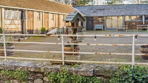 A rustic barn with a feeding station, a wooden fence, and a building with large windows. - 3 Bed in Carnforth (oc-96319) (Yealand Redmayne)