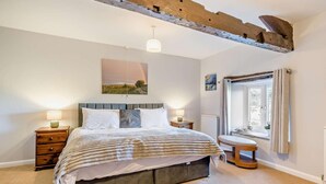 A bedroom with a bed, bedside tables, a window with curtains, a hanging light fixture, and a painting on the wall. - 3 Bed in Carnforth (oc-96319) (Yealand Redmayne)