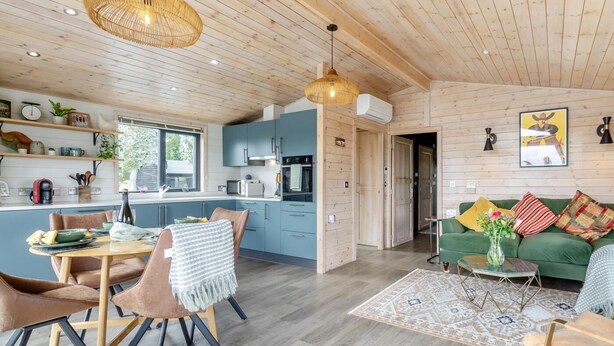 Eine moderne Küche mit Holzschränken, ein Essbereich mit Tisch und Stühlen sowie ein Wohnzimmer mit Sofa und Couchtisch.