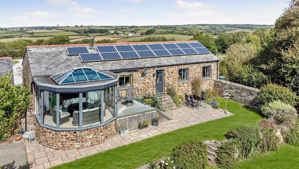 A stone house with a glass conservatory, a solar panel roof, and a well-maintained garden. - 2 Bed in Bude (oc-96290) (Poundstock)