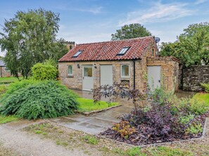 A stone house with a tiled roof, a small garden with various plants, and a paved entrance. - 1 Bed in Pickering (oc-96309) (Allerston)