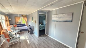 Hotellihuone, jossa on sänky, työpöytä, tuoli, lamppu ja taulu seinällä.