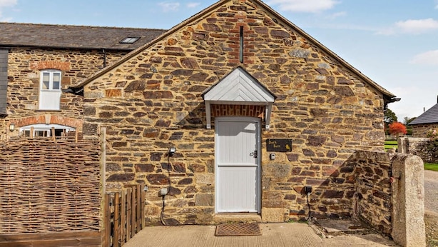 A stone building with a white door, a small window, and a sign reading 'Duck Barn.' - 1 Bed in Launceston (oc-96333) (Saint Giles on the Heath)