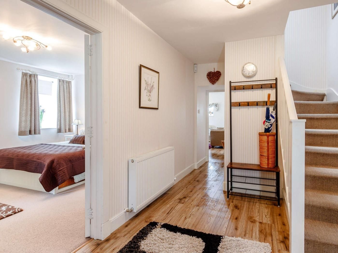 A hotel room with a bed, a radiator, a staircase, and a hallway leading to another room.