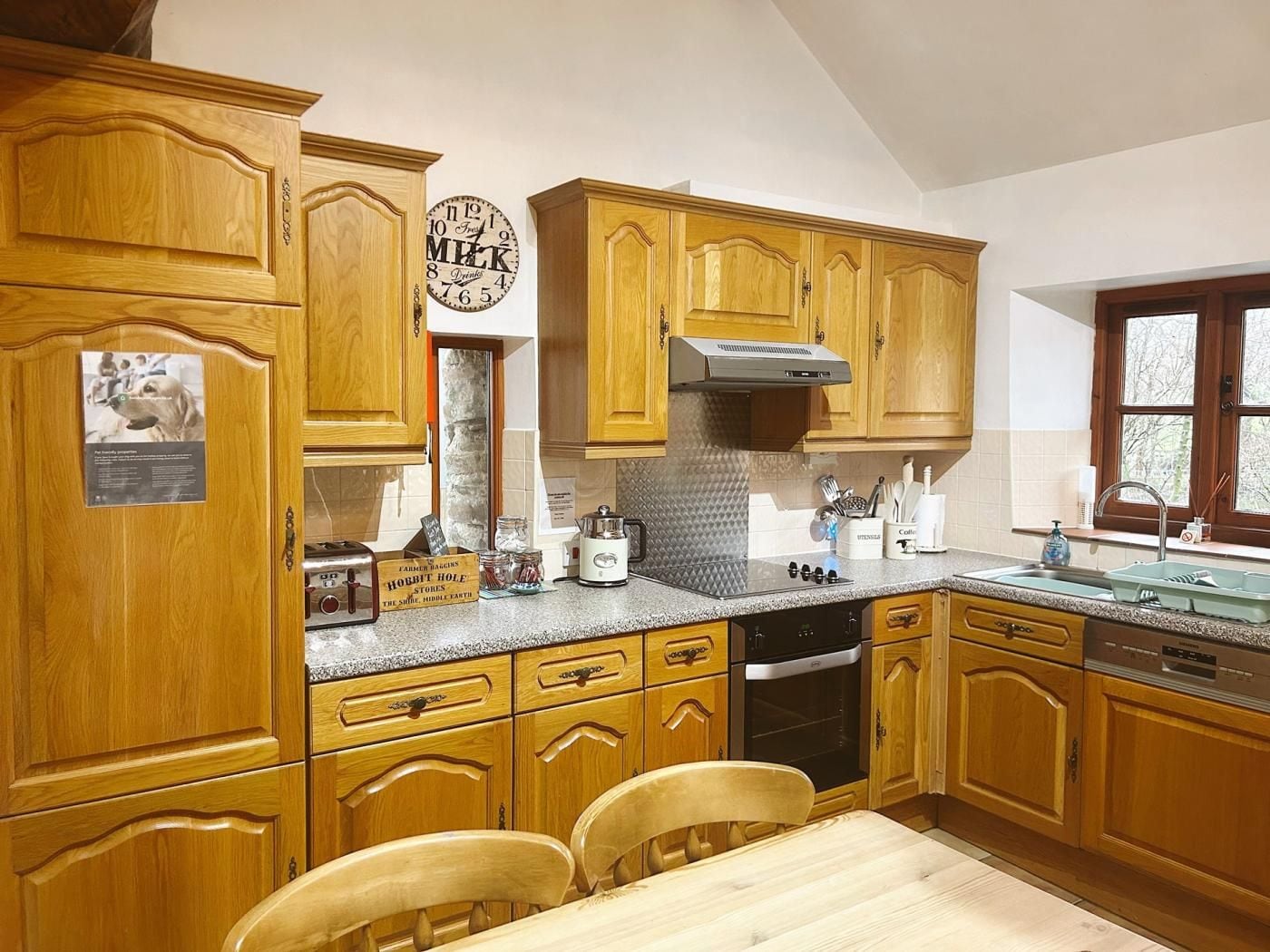 A kitchen with wooden cabinets, a clock, a stove, and a sink.