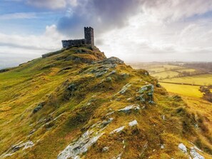 Eine Burg auf einem grasbewachsen Hügel unter blauem Himmel.