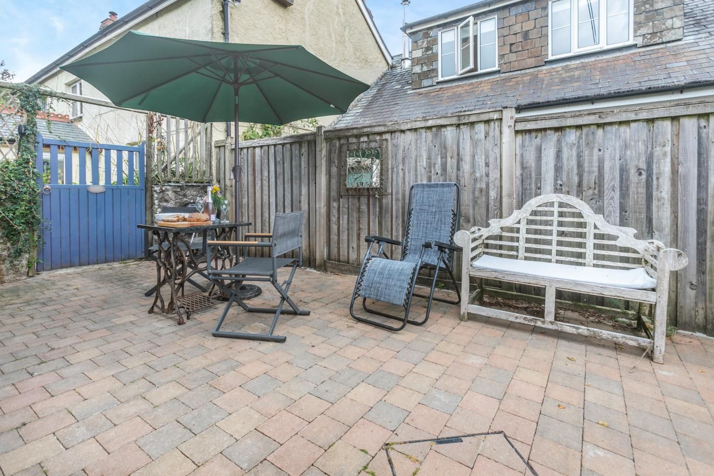 A patio with a table, chairs, a bench, and an umbrella.