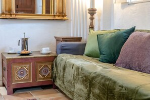 A bed with a green cover, a wooden nightstand with a cup and saucer, and a decorative cabinet with floral patterns. - 1 Bed in Holsworthy (oc-dairc) (Thornbury)