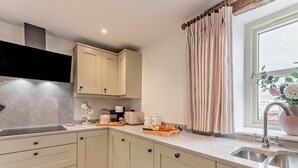 A modern kitchen with light-colored cabinets, a countertop with various appliances, and a window with curtains. - 2 Bed in Carlisle (oc-96302) (Scaleby)