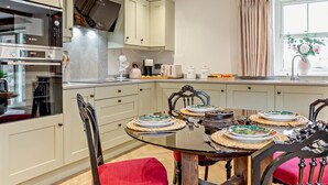 A modern kitchen with a dining table set for four, a Bosch oven, and a window with curtains. - 2 Bed in Carlisle (oc-96302) (Scaleby)