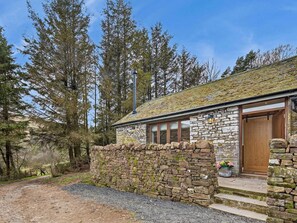 A stone cottage with a wooden door, a chimney, and a stone wall.