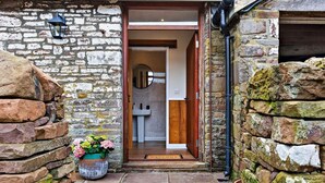 A stone-walled entrance with a wooden door leading to a bathroom with a sink and mirror. - 1 Bed in Brecon (oc-96359) (Cantref)