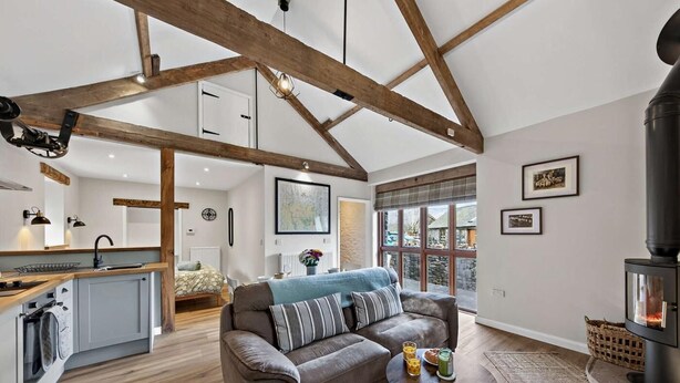 A spacious living area with a sofa, a coffee table, a fireplace, and a kitchen area with a sink and cabinets. - 1 Bed in Brecon (oc-96359) (Cantref)
