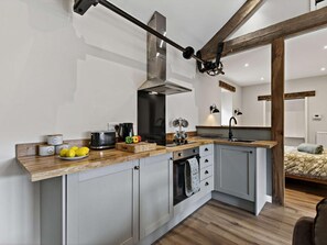 A compact kitchen with a built-in oven, a stovetop, and a hanging pot rack.