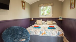 Un dormitorio con cama, una silla, un ventanal y un televisor.