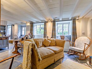 A cozy room with a sofa, a rocking chair, a dining table with chairs, and a kitchen area. - 2 Bed in Newquay (oc-91776) (Cubert)