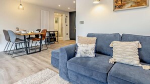 Una sala moderna con un sofá azul, una mesa de comedor con sillas y un cuadro en la pared.