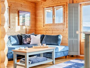A cozy room with a blue sofa, a wooden table with a tray, and a window with shutters.