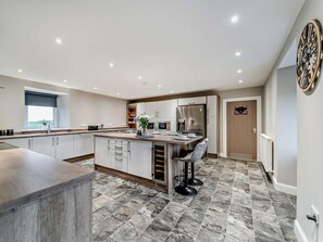 A modern kitchen with a central island, stainless steel appliances, and a dining area with bar stools. - 3 Bed in Girvan (oc-96394) (Girvan)