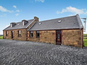A stone building with a sloped roof, multiple windows, and a gravel driveway. - 3 Bed in Girvan (oc-96394) (Girvan)