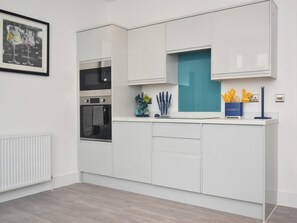 Eine moderne Küche mit weißen Schränken, einer Mikrowelle und einer blauen Spritzschutzwand.