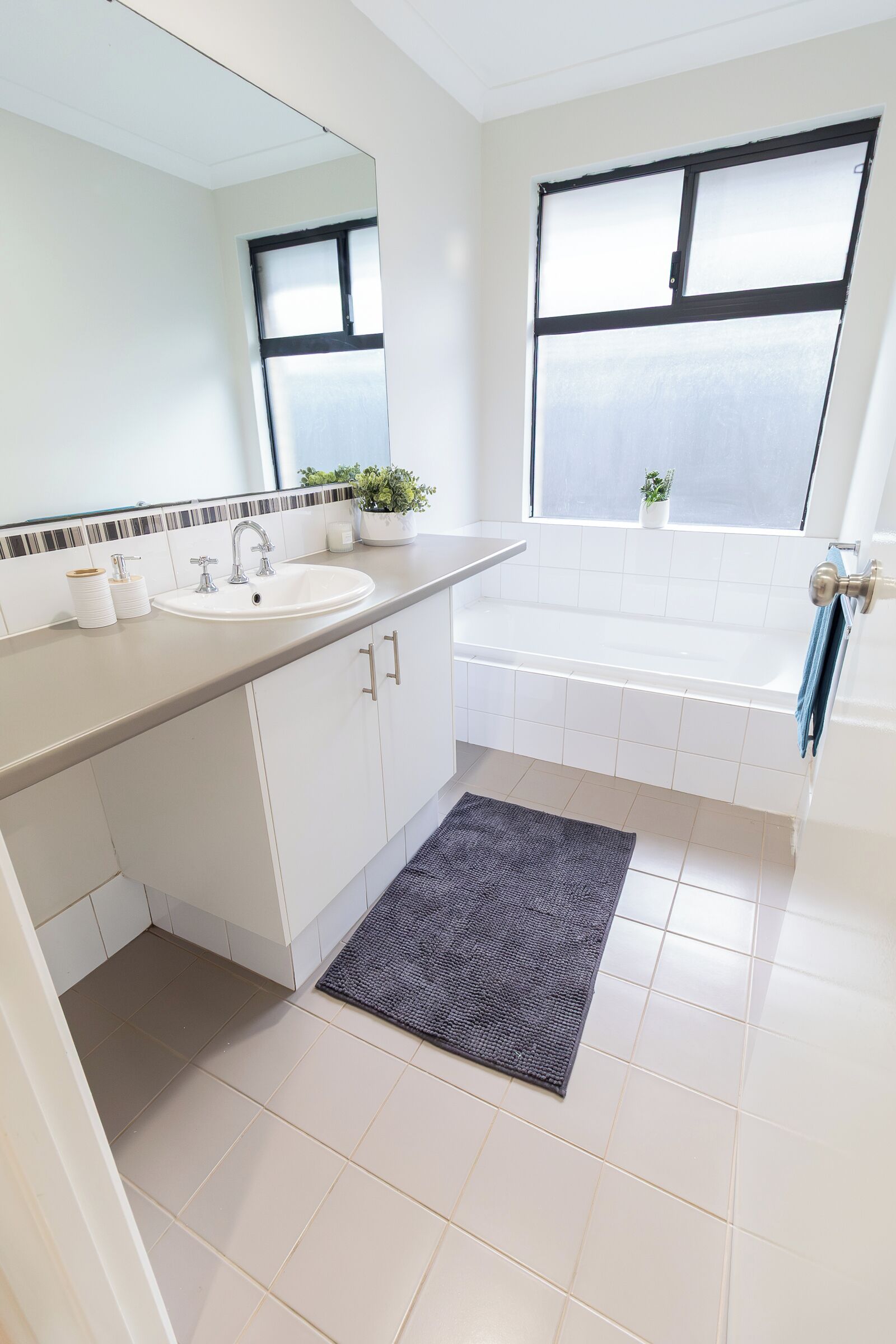 Un baño con lavamanos, espejo, ventana y bañera.