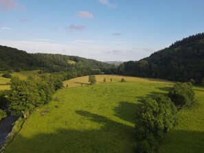 A panoramic view of a green valley with a river, surrounded by hills and trees. - 1 Bed in Tiverton (oc-96405) (Washfield)