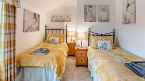 Een slaapkamer met twee bedden, een kroonluchter en kunstwerken aan de wanden.