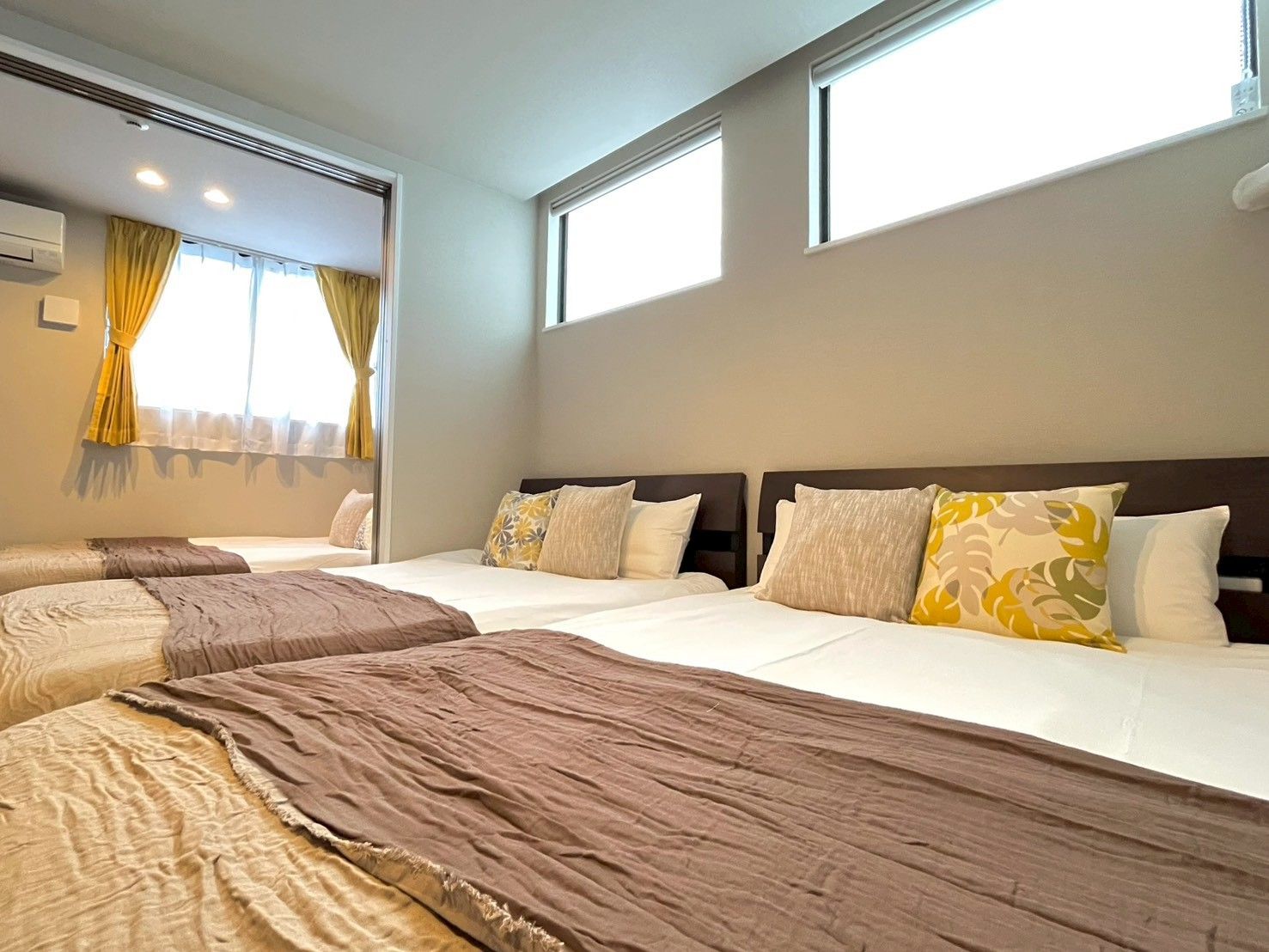 A hotel room with two beds, a large window, and a ceiling fan.