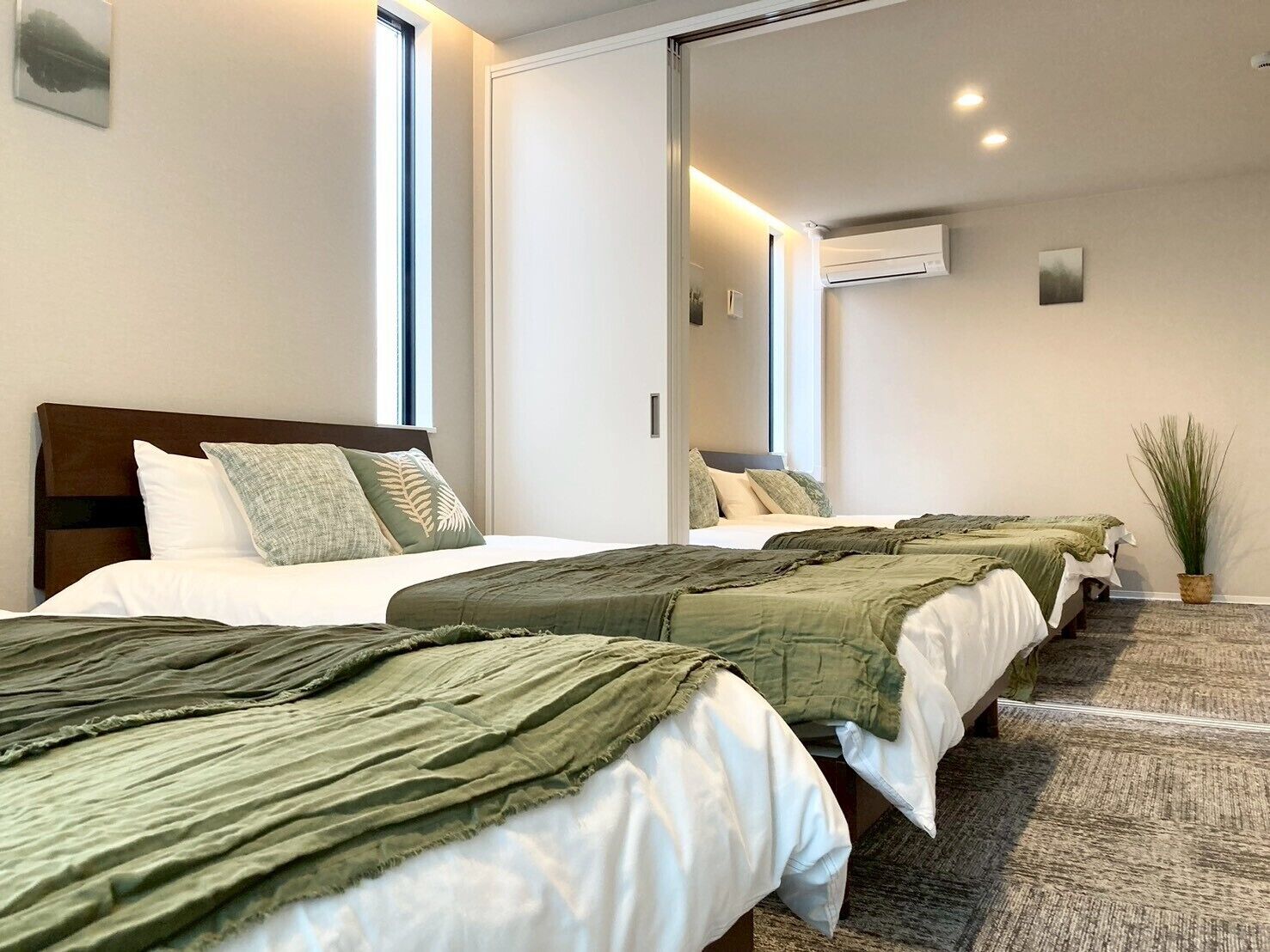 A hotel room with two beds, a large mirror, and an air conditioning unit.