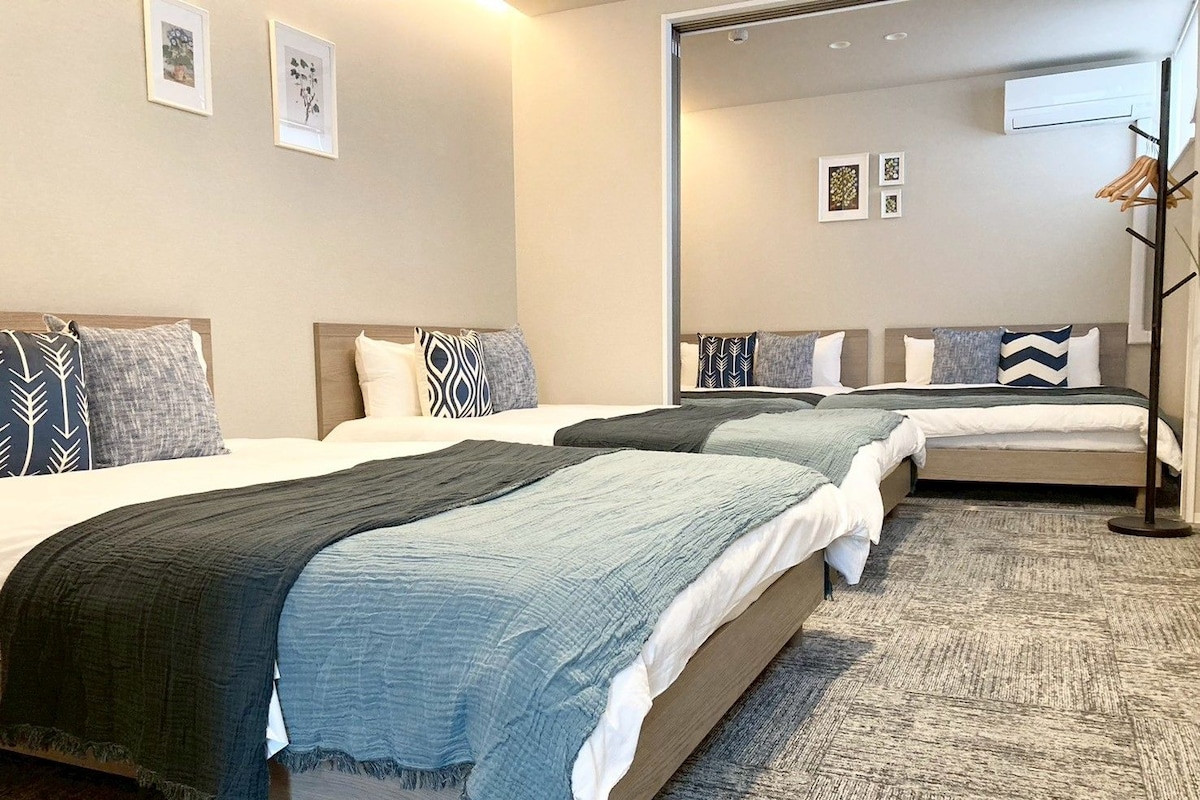 Quarto de hotel com três camas, um espelho grande e um guarda-roupa.
