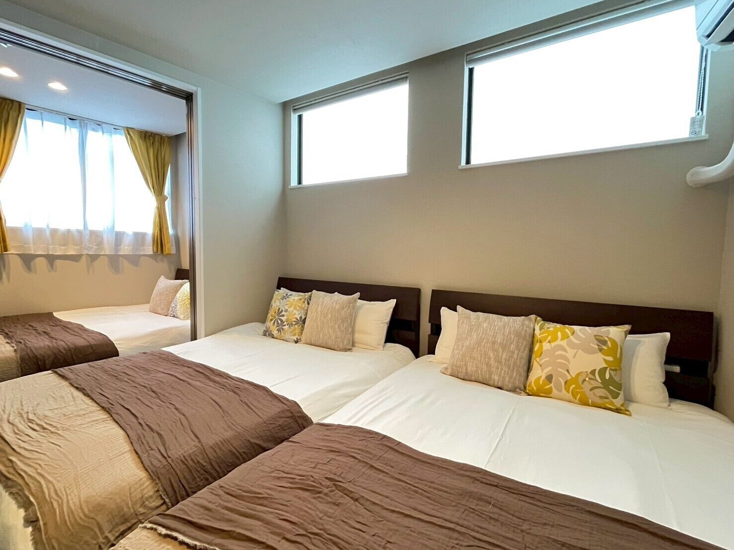 A hotel room with two beds, a window, and a ceiling fan.