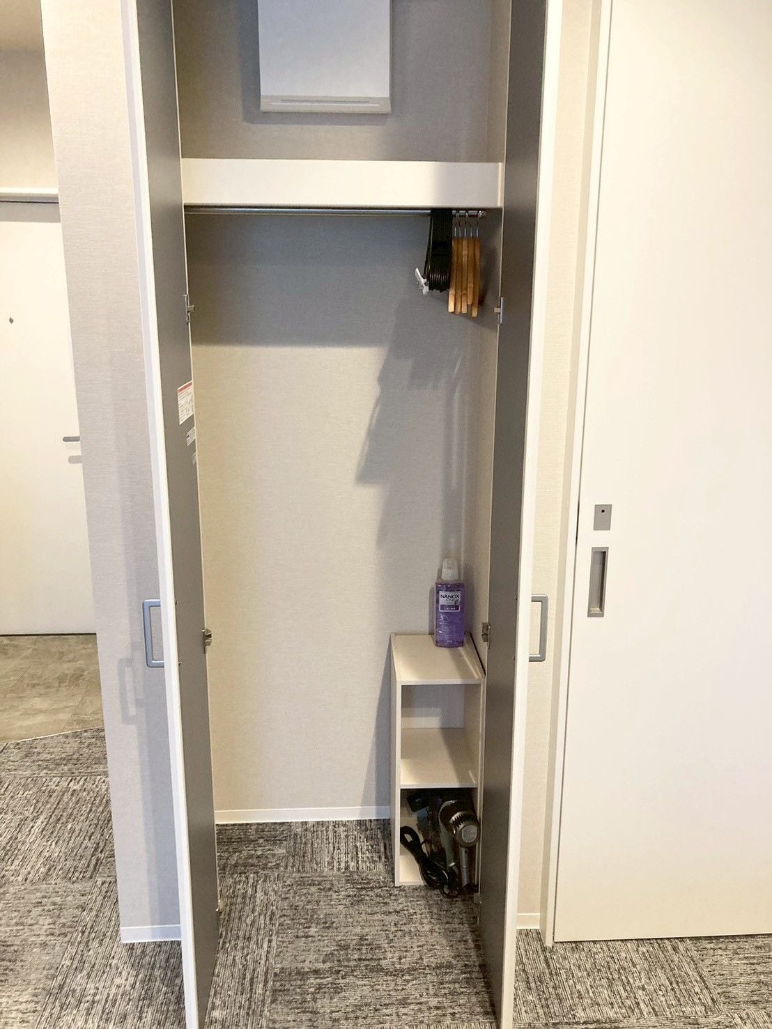 Um closet espaçoso com estantes, cabideiro e um pequeno armário.