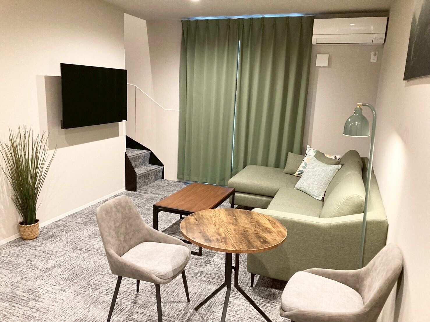 Ett modernt vardagsrum med en soffa, två fåtöljer, ett soffbord, en platt-TV och en lampa.