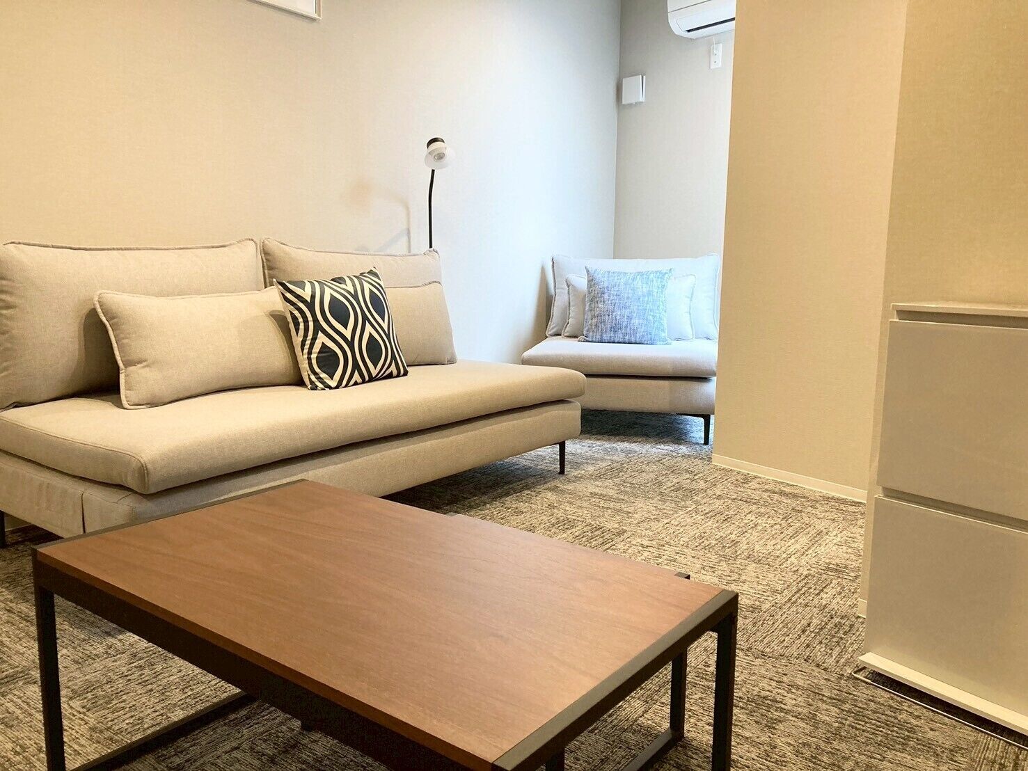 Una sala de estar con sofá, mesa de centro y un cojín decorativo estampado.