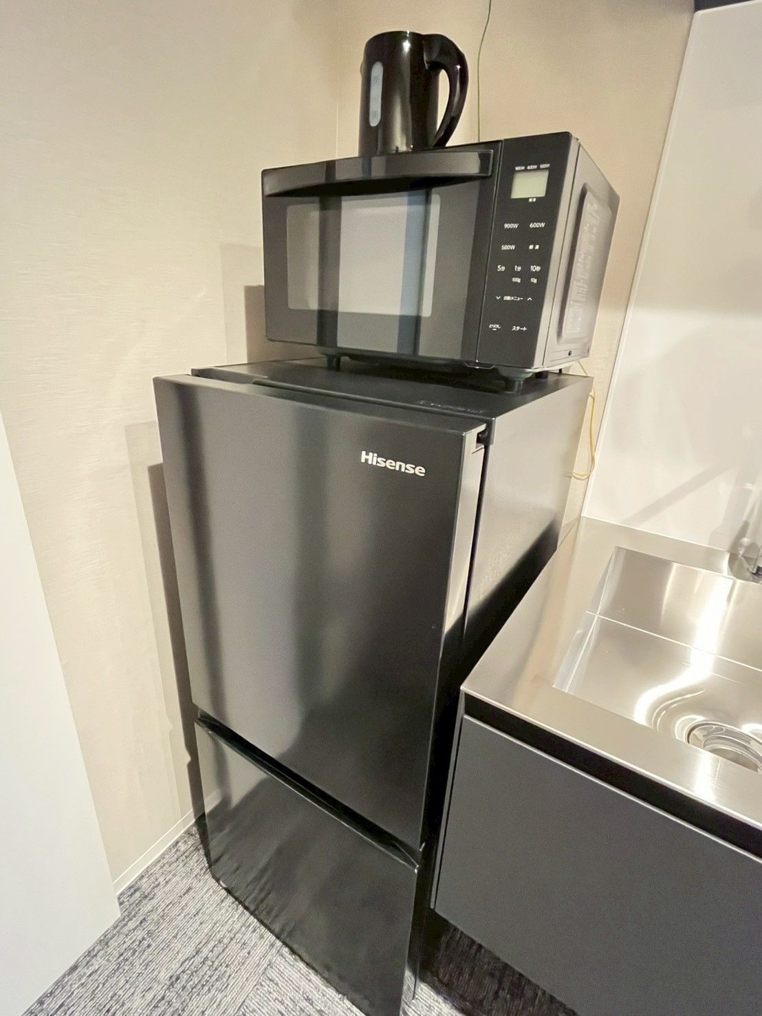 Een compact keuken met een Hisense koelkast, een magnetron en een roestvrijstalen spoelbak.