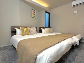 Quarto de hotel com duas camas, uma janela grande e um ar-condicionado.