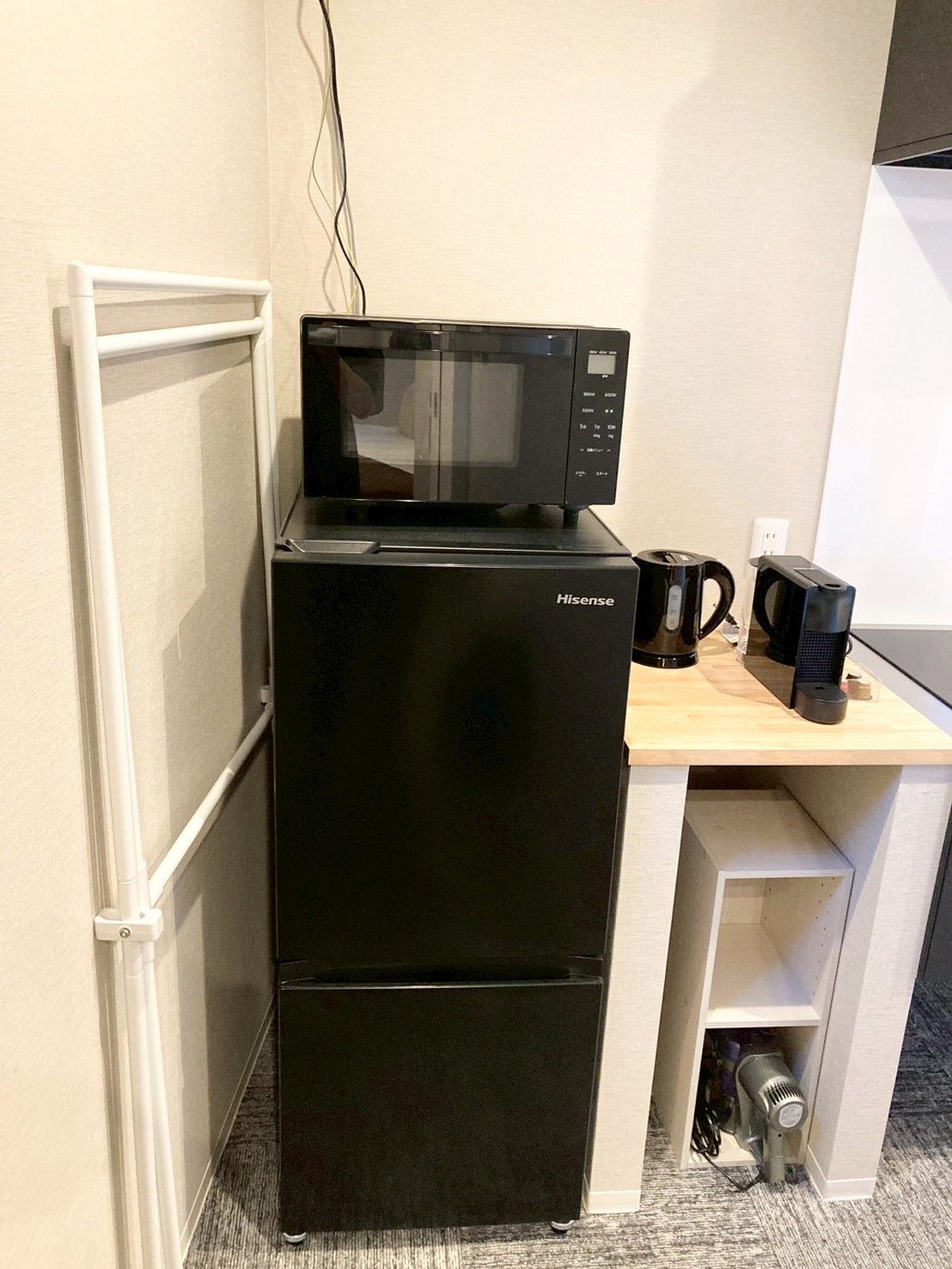 A compact kitchenette with a black Hisense microwave, a coffee maker, and a hairdryer.