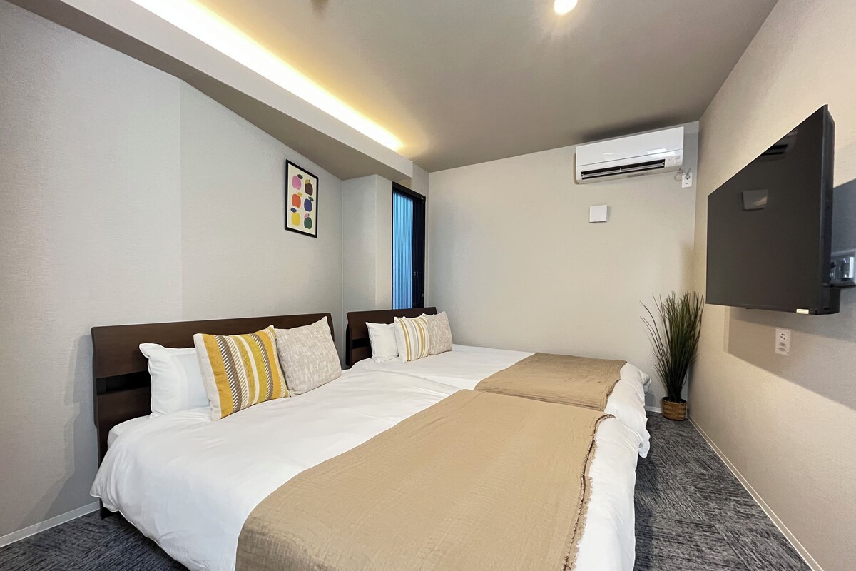 Quarto de hotel com cama grande, televisão de tela plana, ar condicionado e janela com persianas.