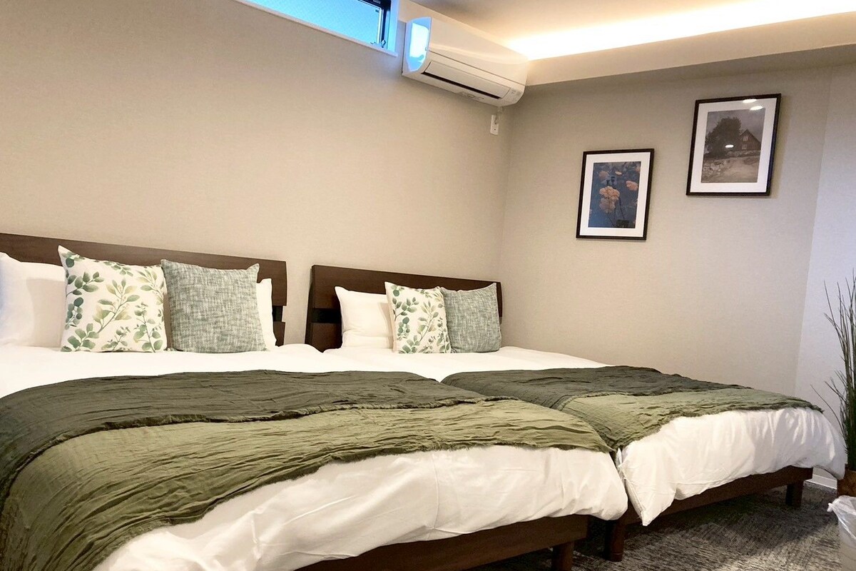Uma cama de casal com cabeceira, duas almofadas e um cobertor verde.