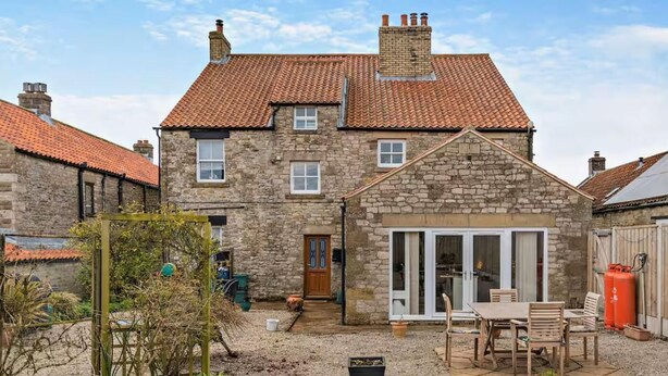 A stone house with a tiled roof, a patio with a table and chairs, and a gravel yard. - 6 Bed in Pickering (oc-96415) (Newton-on-Rawcliffe)