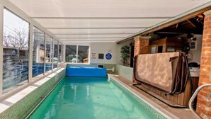 A swimming pool with clear blue water, a blue seating area, and a covered bench. - 6 Bed in Pickering (oc-96415) (Newton-on-Rawcliffe)