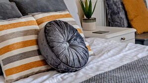 A neatly arranged bed with striped pillows, a round pillow, and a small potted plant on a bedside table. - 6 Bed in Pickering (oc-96415) (Newton-on-Rawcliffe)