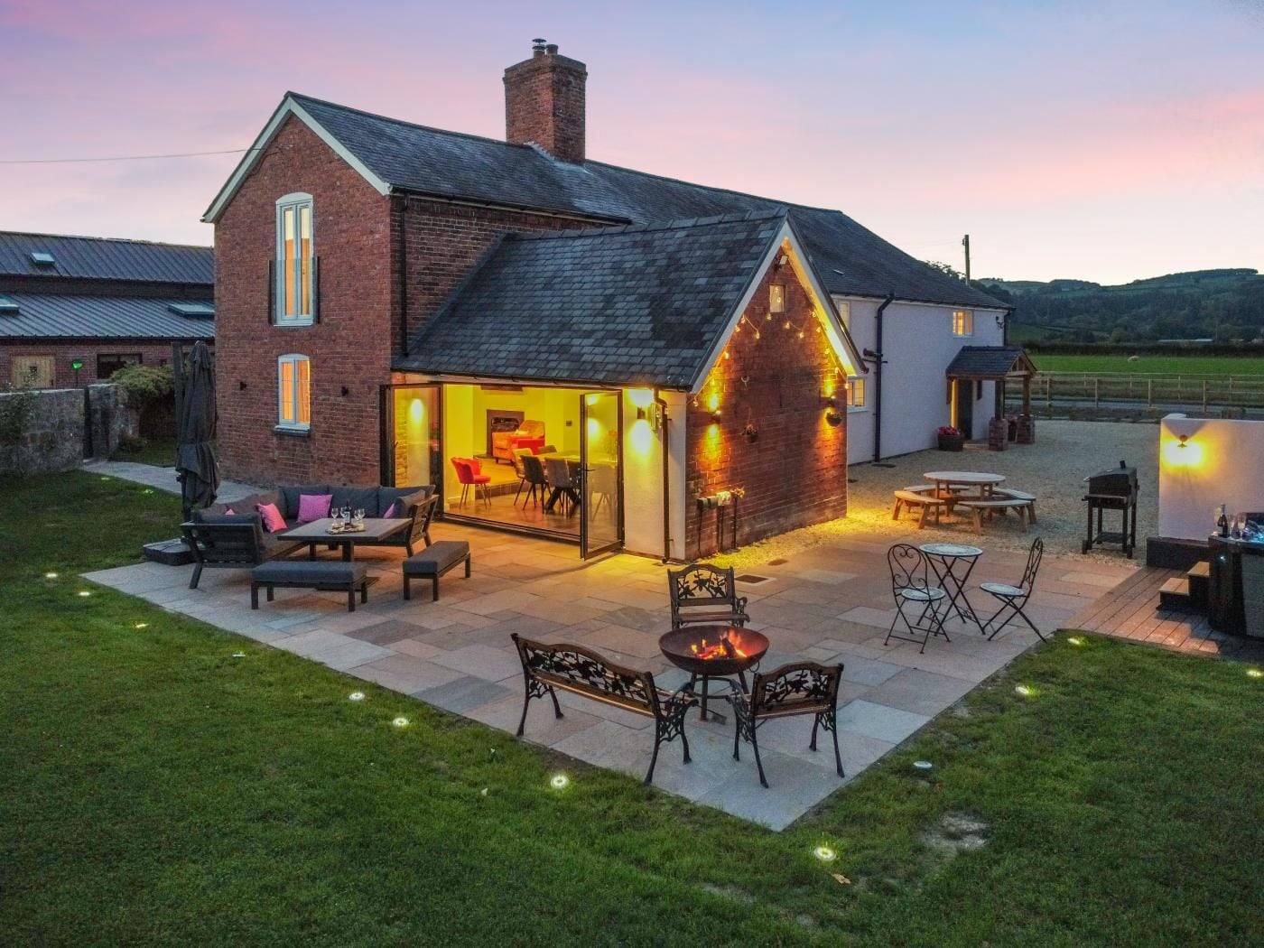 A two-story house with a patio area featuring outdoor seating and a fire pit.