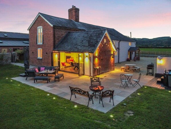 A two-story house with a patio area featuring outdoor seating and a fire pit.