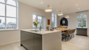 Una cucina moderna con isola centrale, ampie finestre e lampade a sospensione.