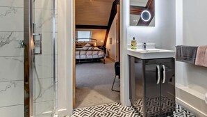 Un bagno moderno con doccia, lavabo con specchio e pavimento decorato.