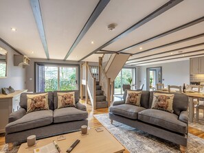 A modern living room with two grey sofas, a coffee table, and a staircase leading to an upper level.
